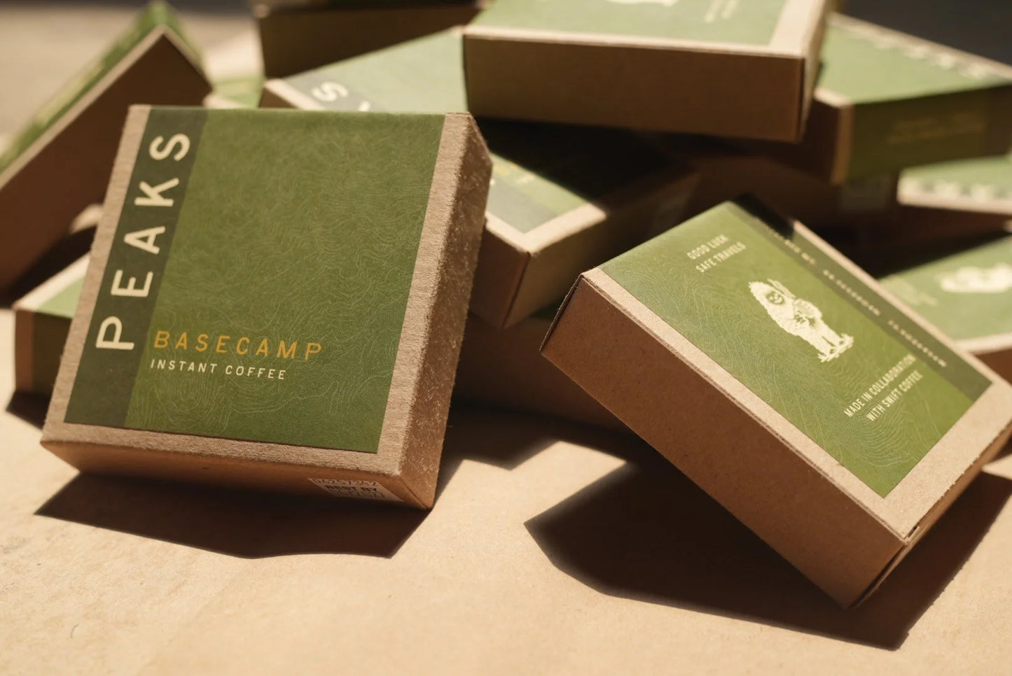 Boxes of Peaks Basecamp instant coffee on a brown surface