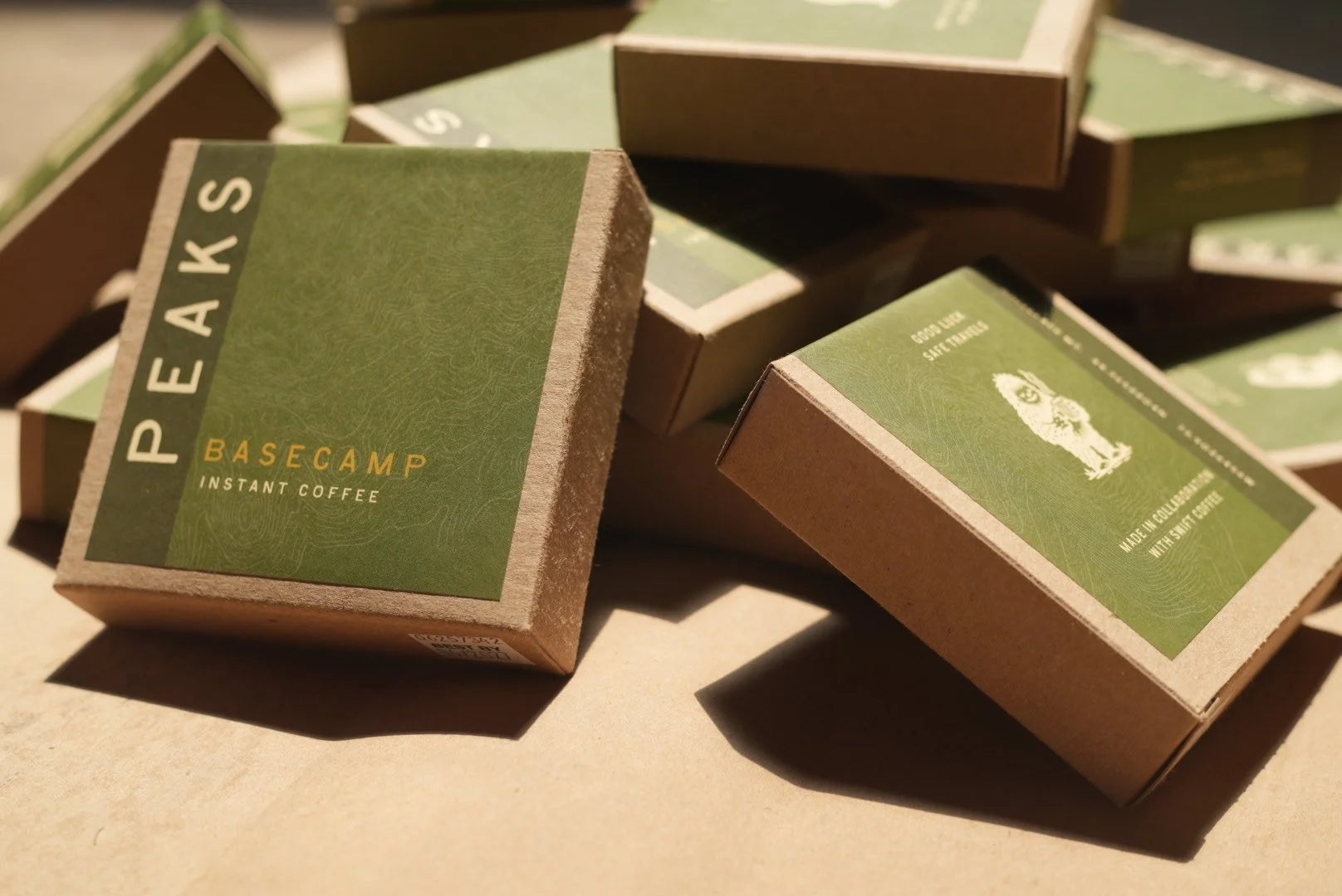 Boxes of Peaks Basecamp instant coffee on a brown surface