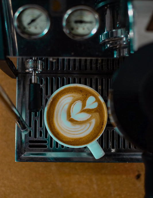 Espresso machine with a cup of coffee featuring latte art on a wooden surface