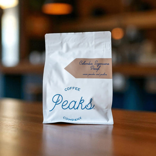 Coffee Peaks Company package on a wooden surface with a blurred background